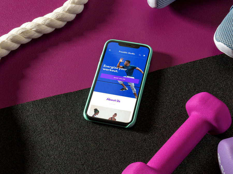 A mobile screen with a fitness app, a couple of pink colored dumbbells, and a skipping rope
