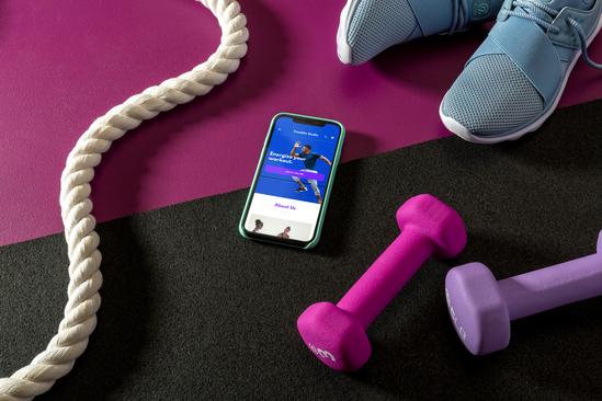 A mobile screen with a fitness app, a couple of pink colored dumbbells, and a skipping rope.